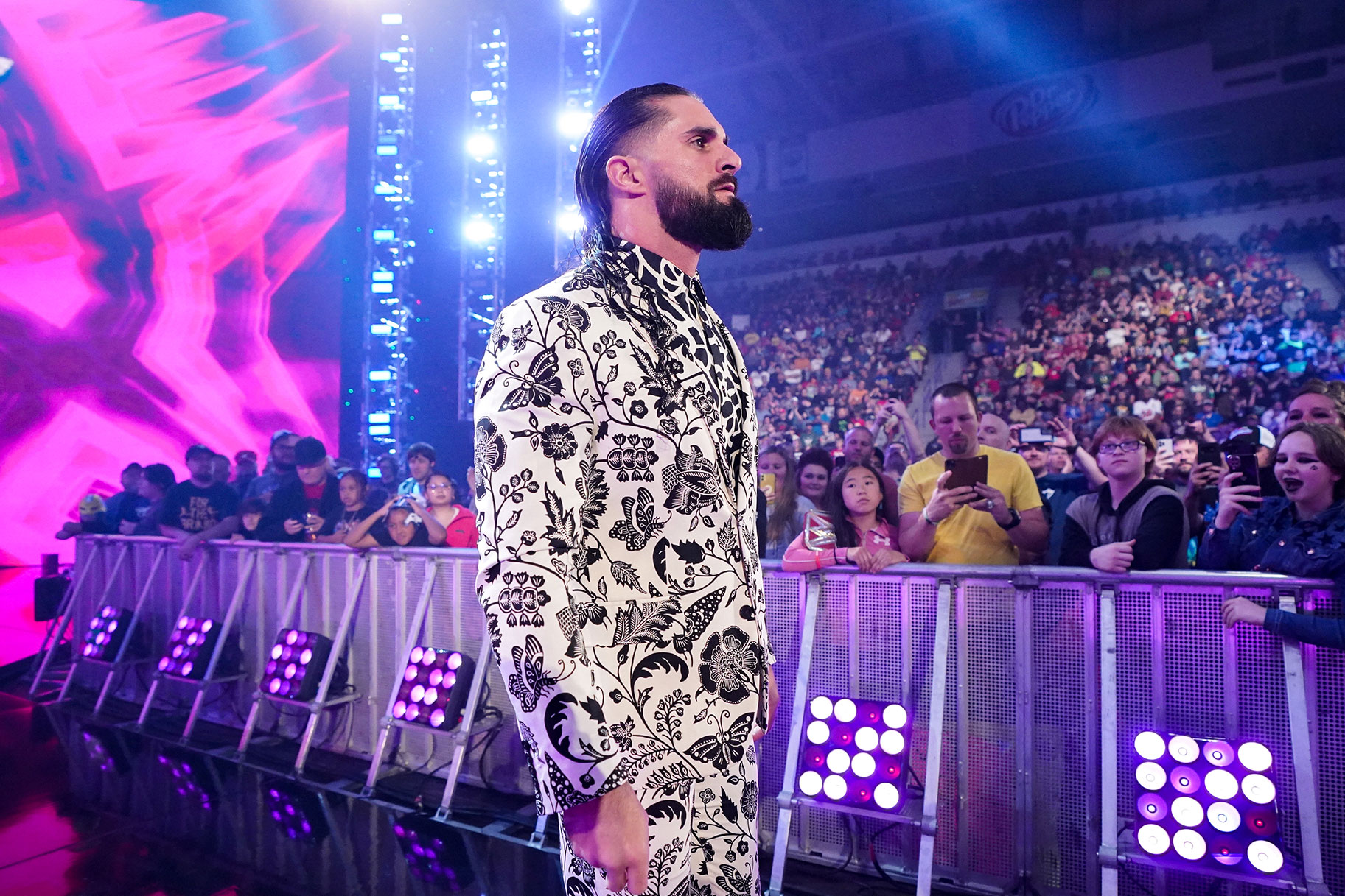 Seth Rollins walking to the ring wearing a black and white, patterned suit