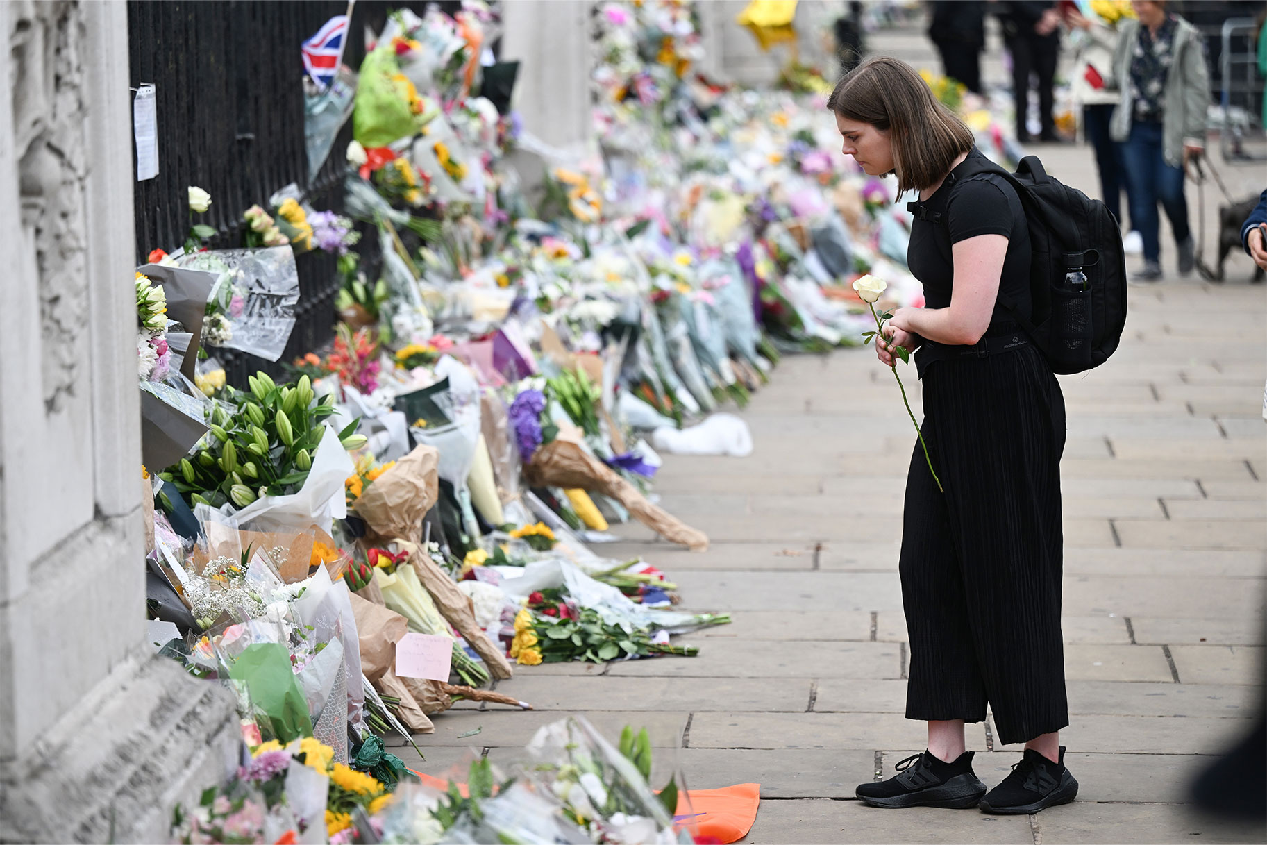 Woman placing flowers against the gate of Buckingham Palace