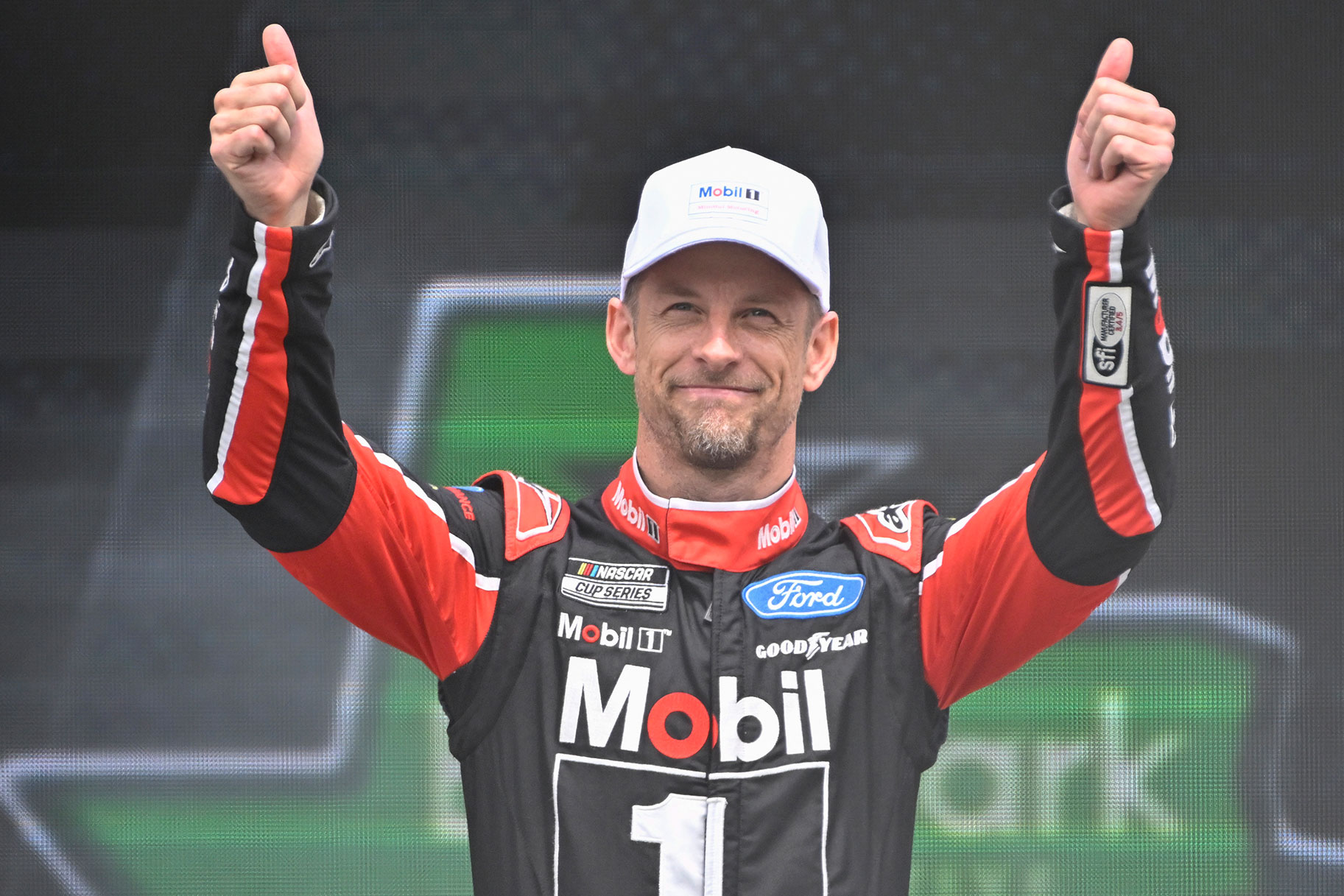 Jenson Button, driver of the #15 Mobil 1 Ford, gives a thumbs up to fans as he walks onstage during driver intros prior to the NASCAR Cup Series EchoPark Automotive Grand Prix at Circuit of The Americas