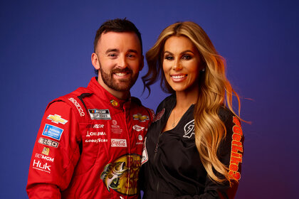 Whitney And Austin posed and smiling against a dark blue backdrop