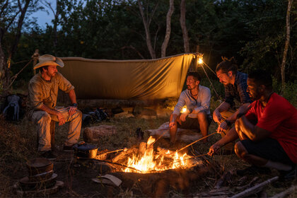 Snake In The Grass Contestants sitting around a campfire