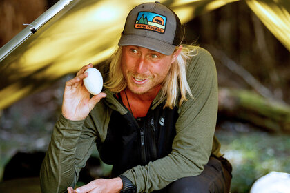 Creighton Baird holds up an egg in Race to Survive: New Zealand