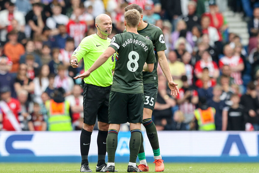 Two football players arguing with a referee