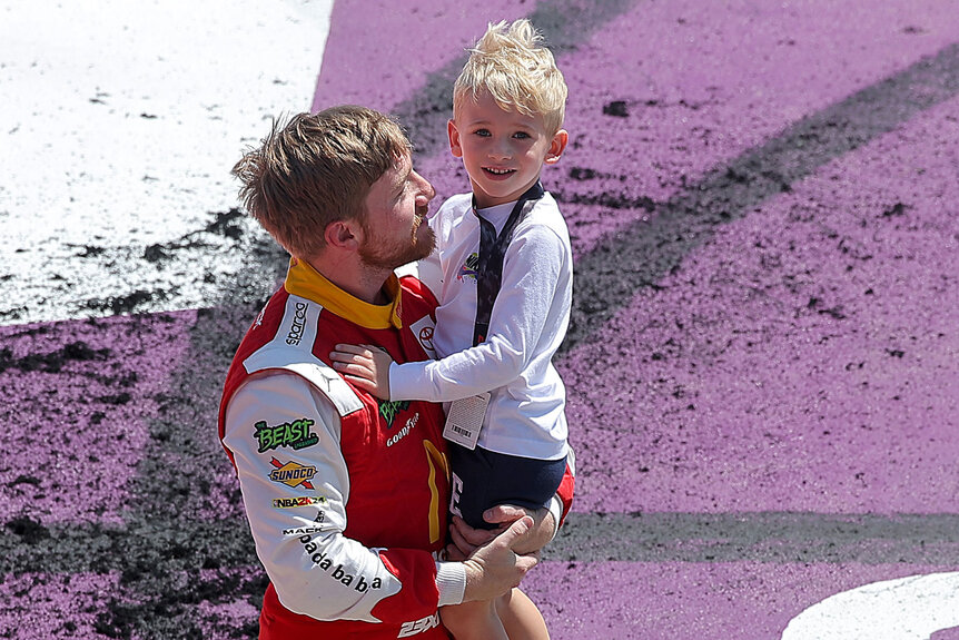 Tyler Reddick holds his son, Beau Reddick after winning the NASCAR Cup Series FireKeepers Casino 400