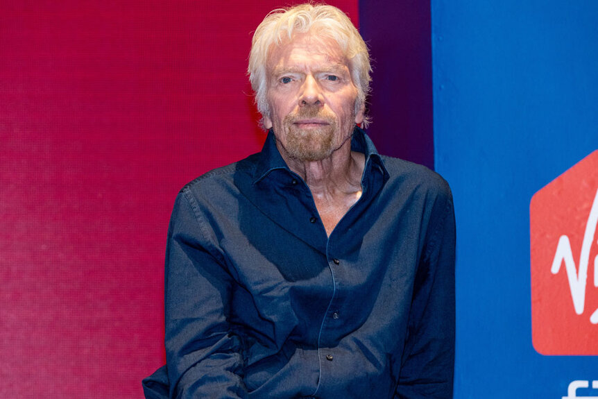 Richard Branson wearing a blue button down shirt at a Virgin event